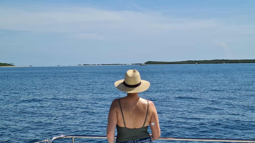 Frau mit braunem Sonnenhut und braunem Tanktop sitzt tagsüber auf dem Boot