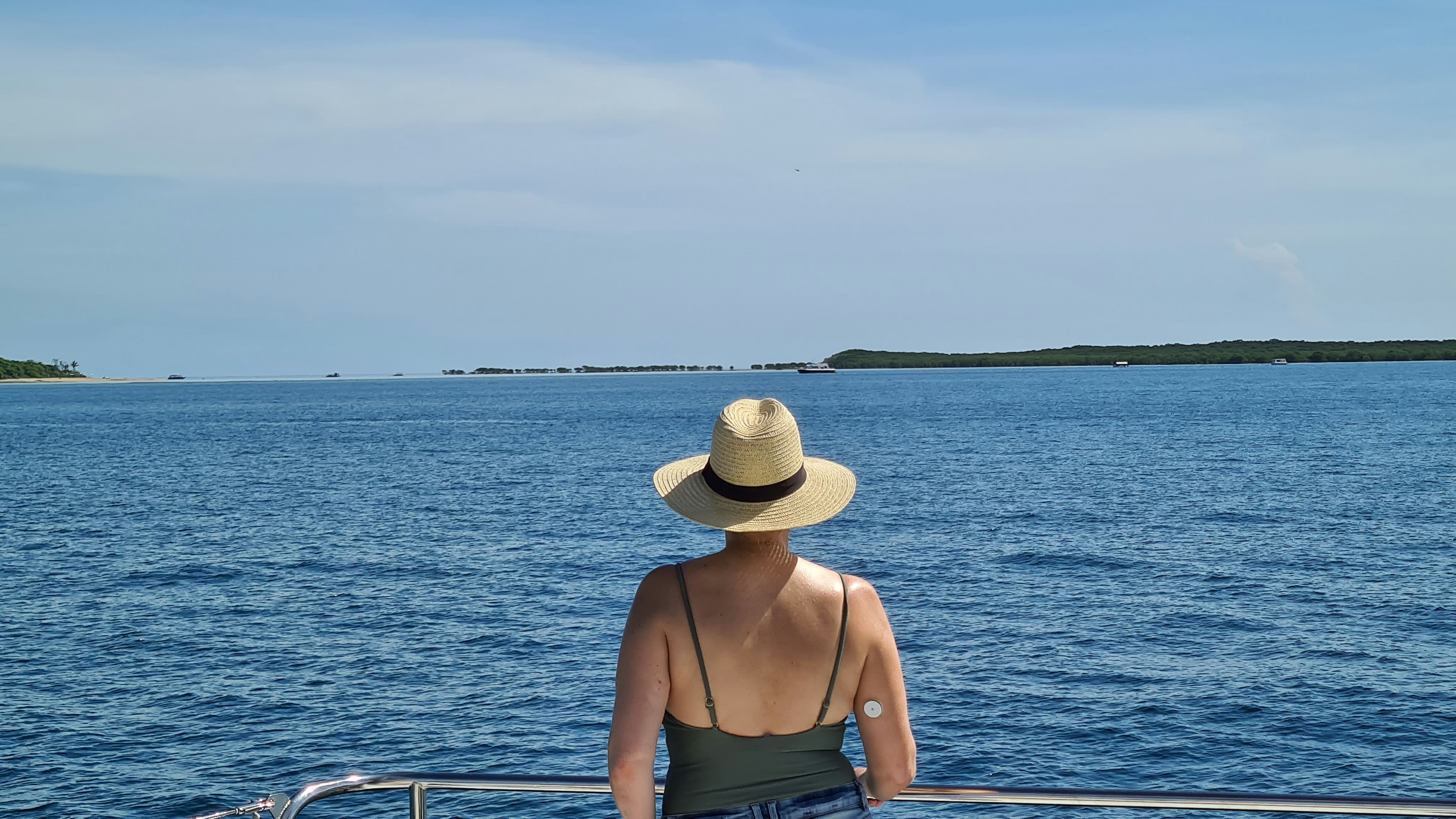 Woman looking over the water to tropical island from yacht in far north Queensland