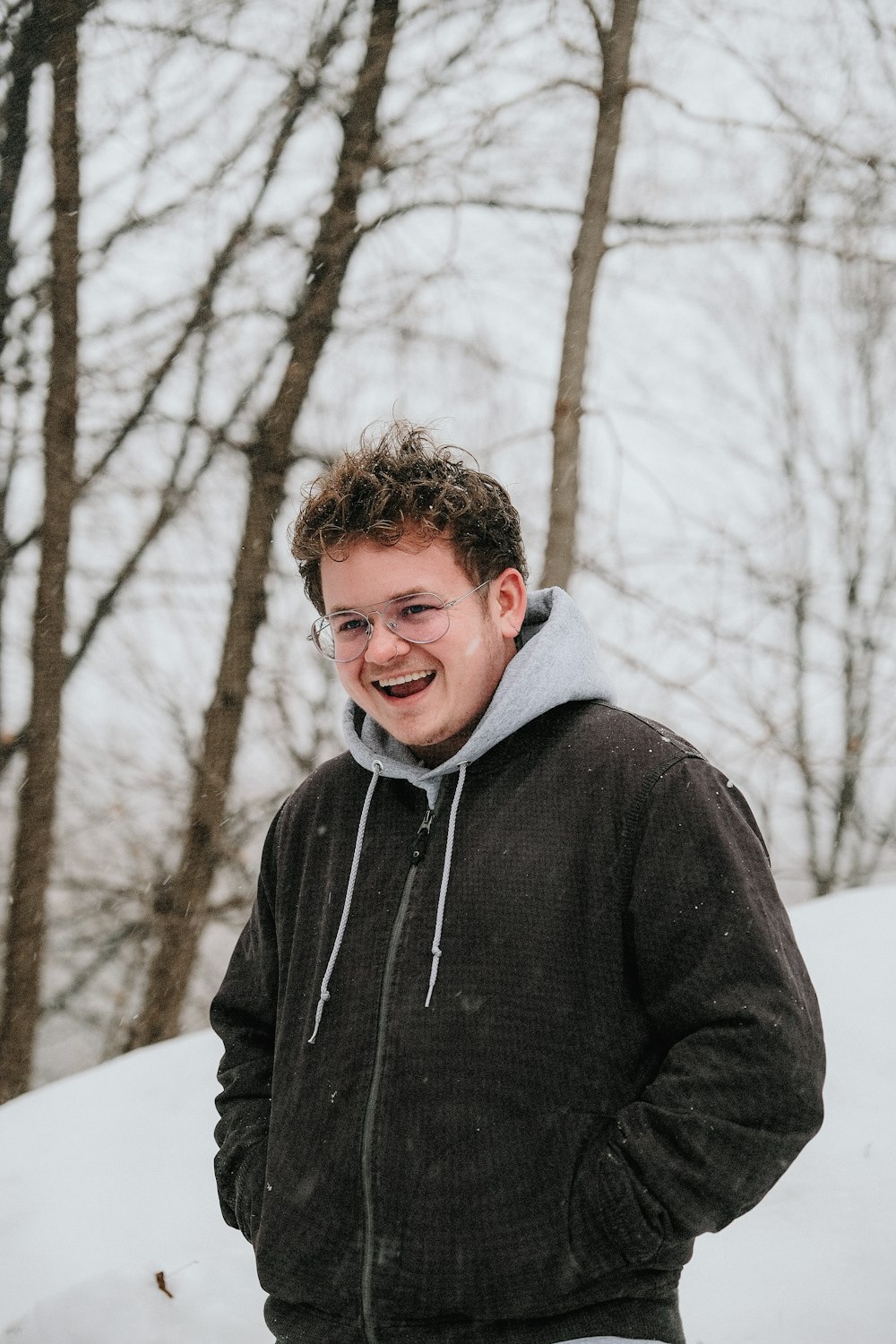 man in black zip up jacket standing on snow covered ground during daytime