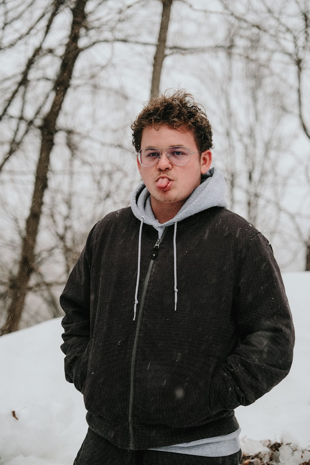 man in black zip up jacket standing on snow covered ground during daytime