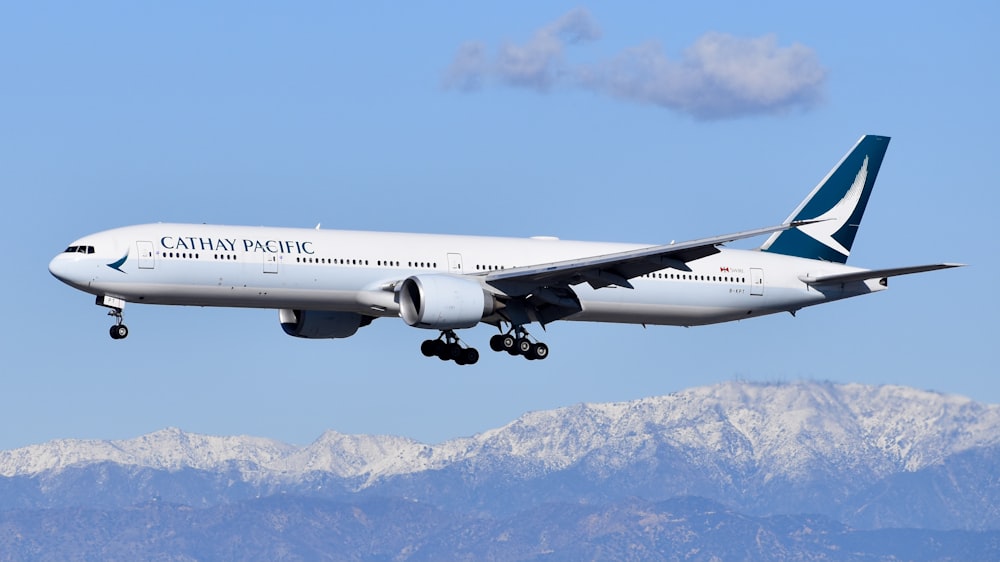 Avión de pasajeros blanco volando sobre una montaña cubierta de nieve durante el día