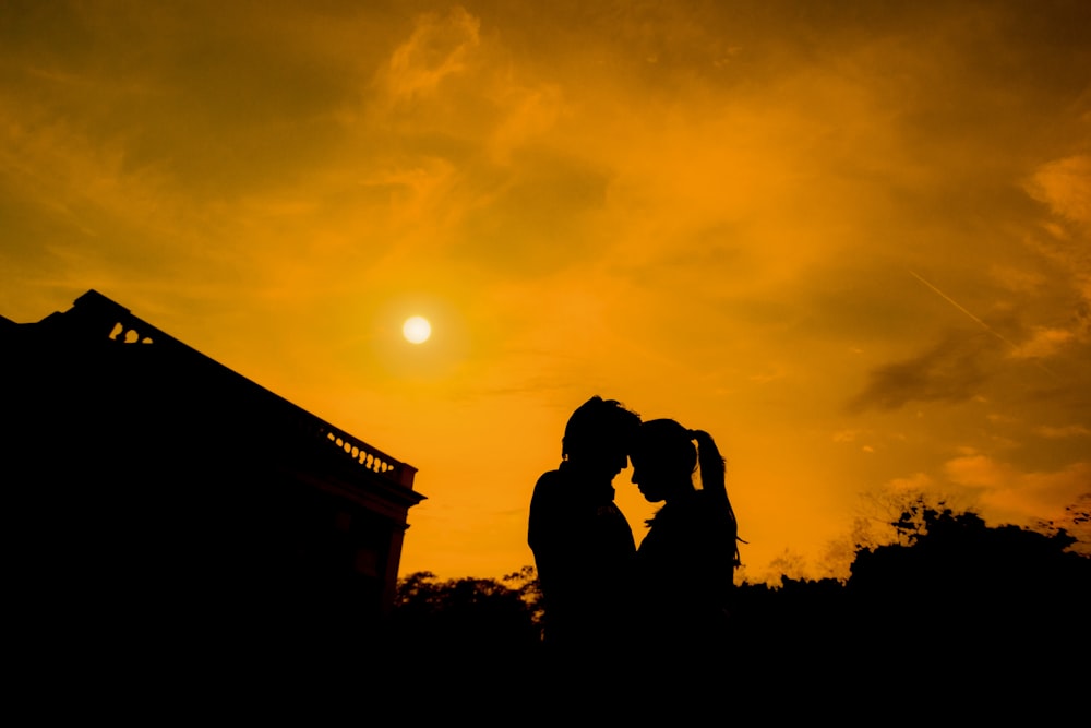 silhouette of man and woman kissing during sunset