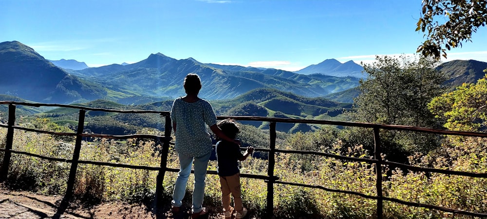 man and woman standing on balcony looking at mountains during daytime