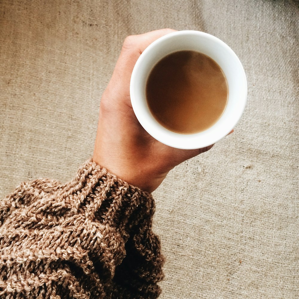 person holding white ceramic mug