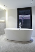 white ceramic bathtub near window