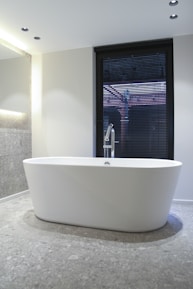 white ceramic bathtub near window
