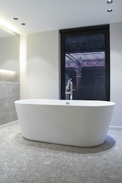 white ceramic bathtub near window