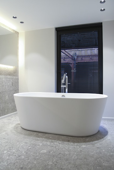 white ceramic bathtub near window