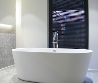 white ceramic bathtub near window