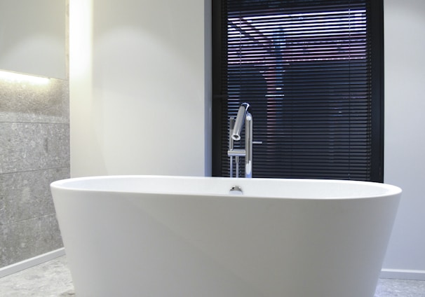 white ceramic bathtub near window