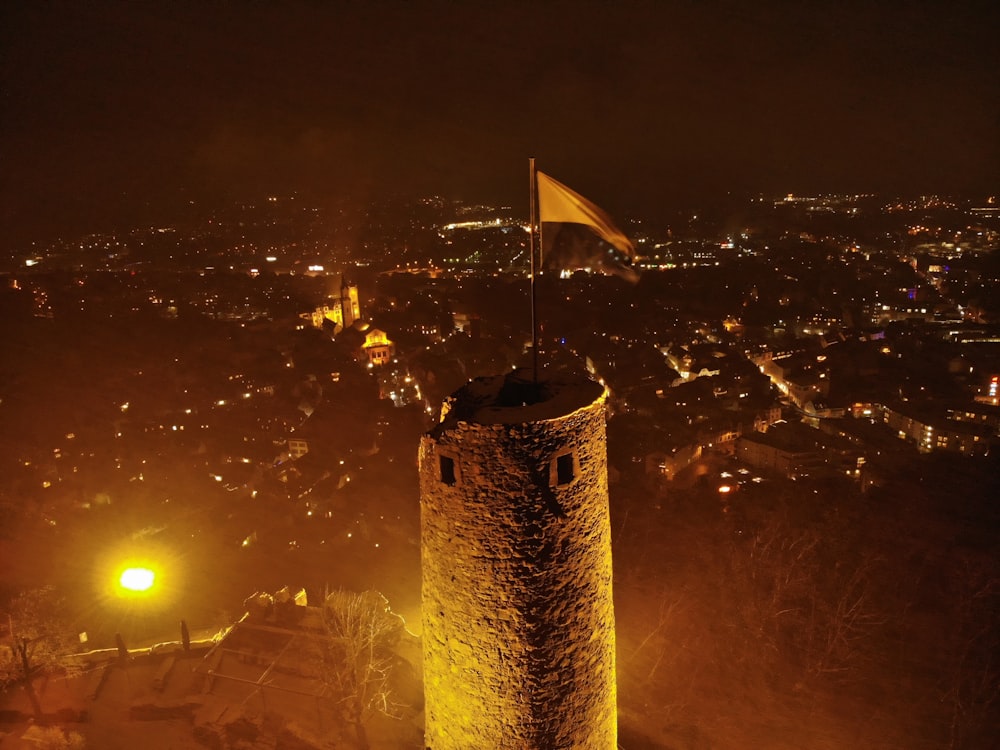 torre de concreto marrom com bandeira de nós um durante a noite