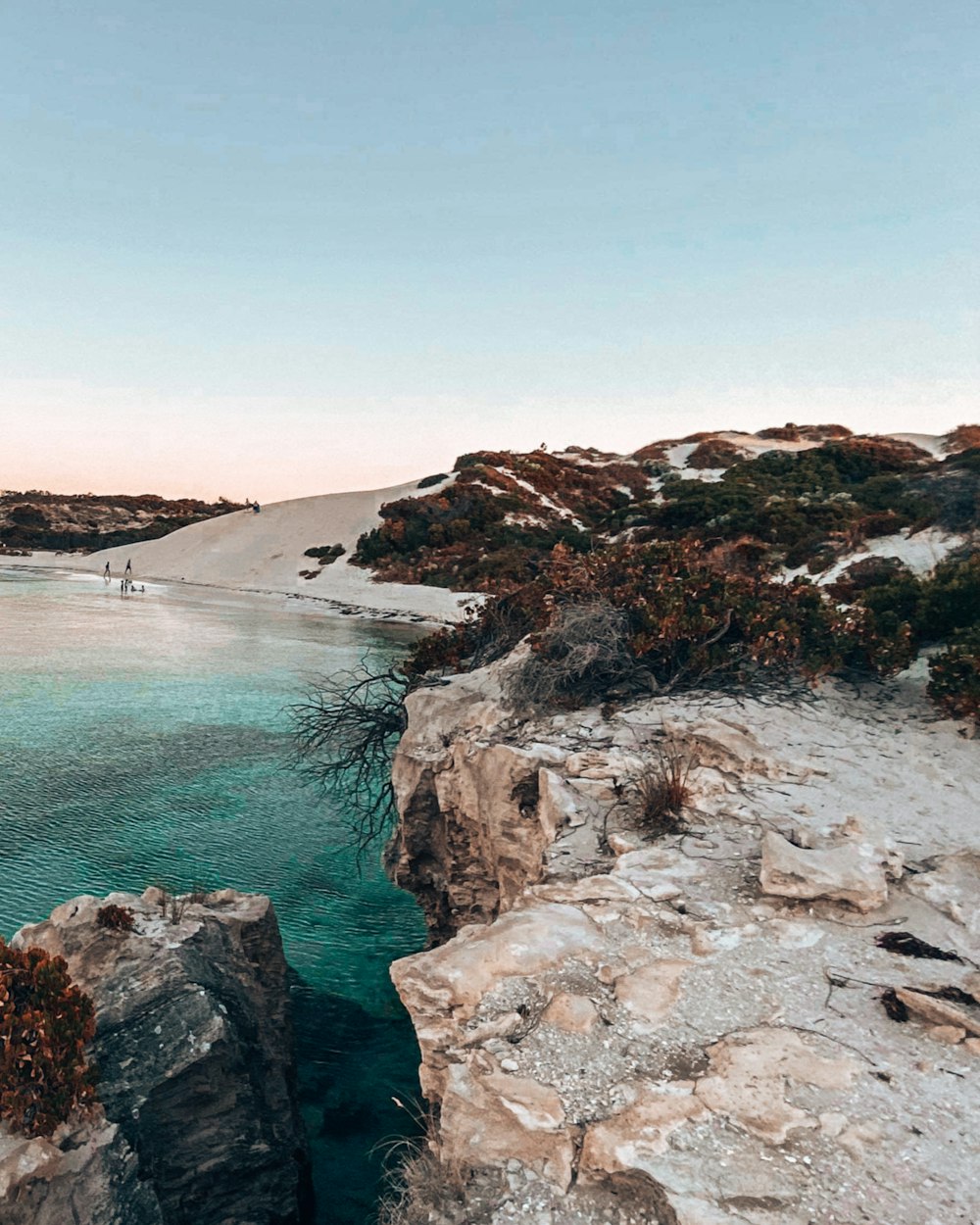 brown rocky mountain beside blue sea under blue sky during daytime