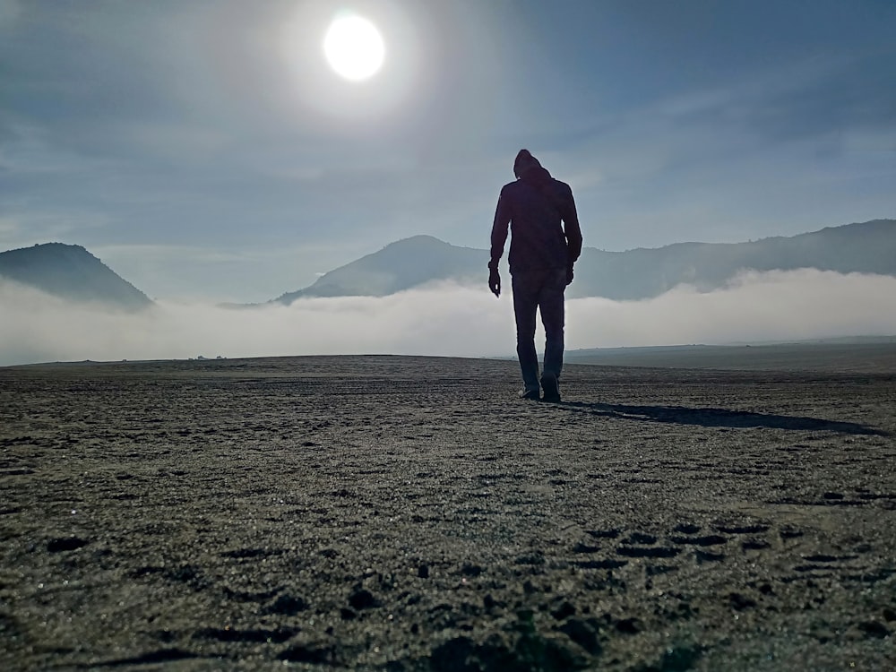 uomo in giacca nera in piedi su campo marrone durante il giorno