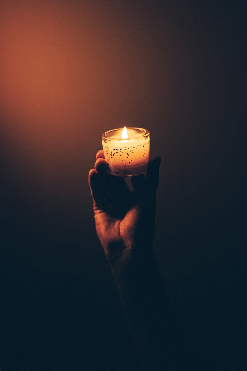 person holding lighted candle in dark room