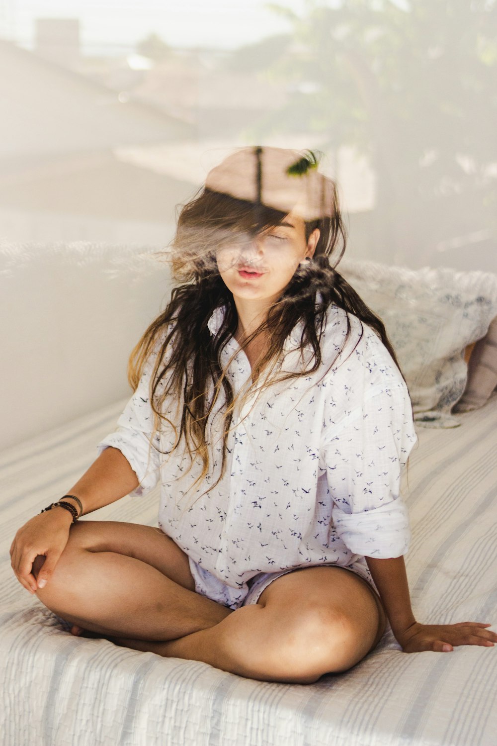 woman in white and blue floral button up shirt sitting on white bed