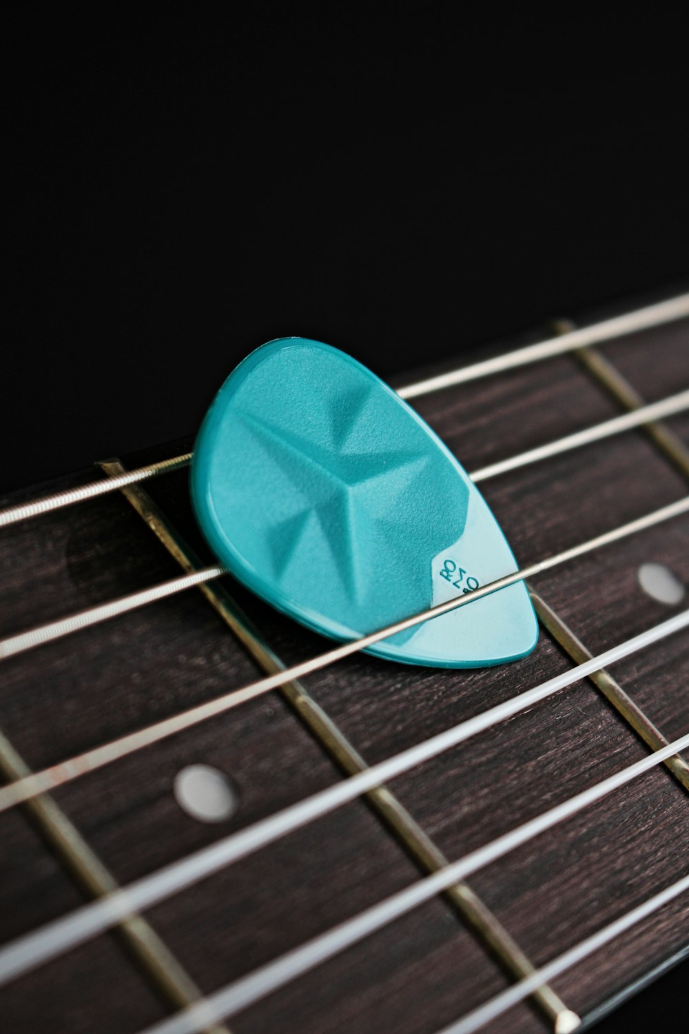 blue guitar pick on brown guitar