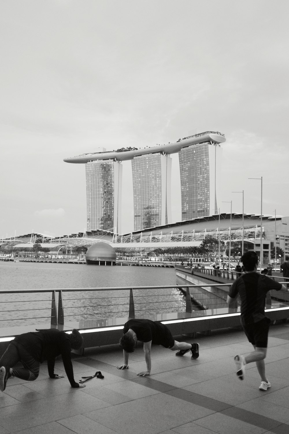 grayscale photo of people sitting on bench near body of water