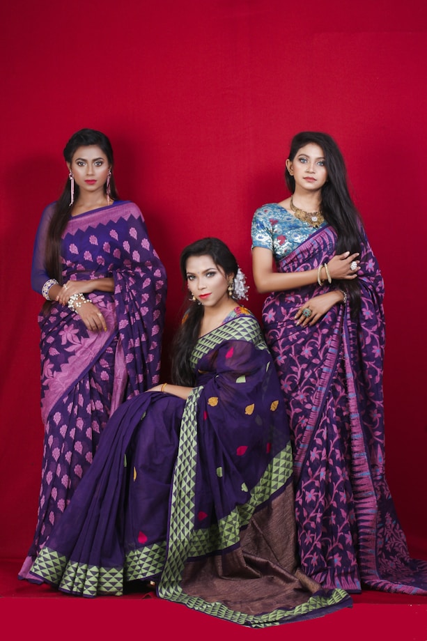 Three women in purple and pink sarees