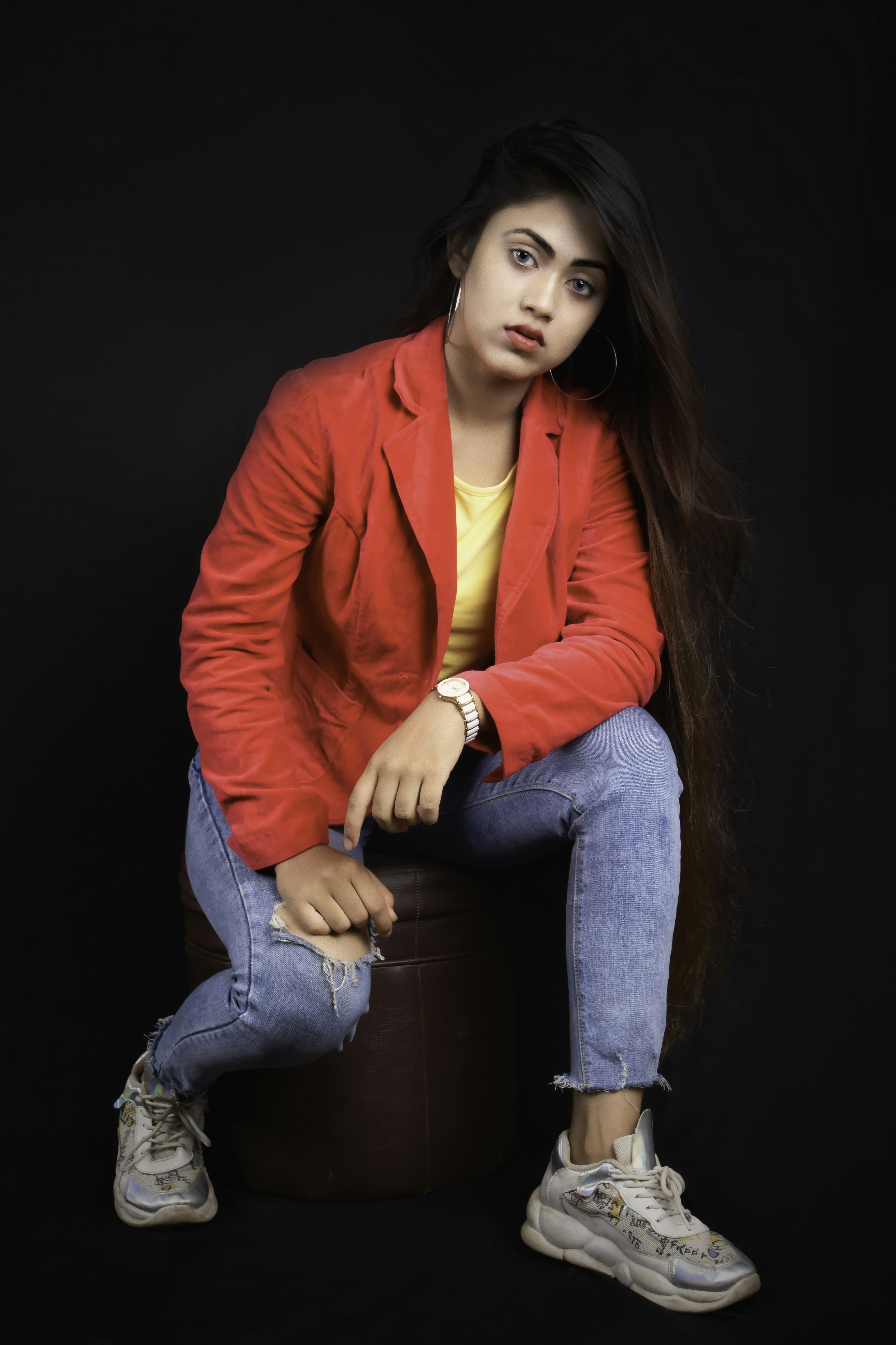 茶色の木製の座席に座る赤いブレザーと青いデニムジーンズの女性