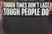 A rectangular sign displays the motivational phrase 'Tough times don't last, tough people do' in bold, white capital letters on a black background.