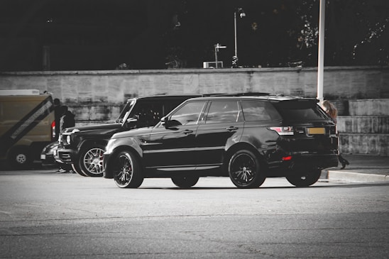 A sleek black and gray private taxi car parked in an urban setting at dusk.