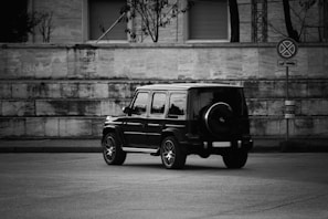 grayscale photo of suv parked beside wall