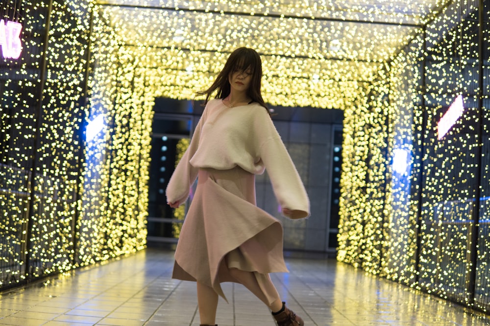 woman in white long sleeve shirt and brown skirt standing on white floor tiles