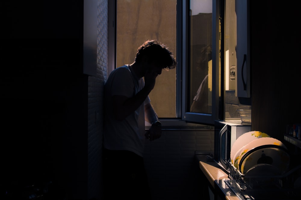 woman in white shirt standing beside window