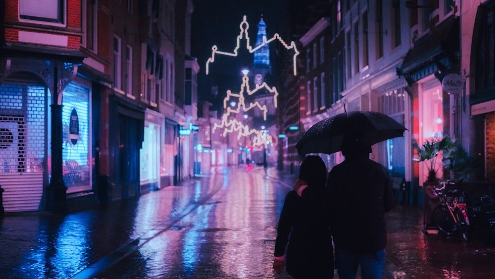 person in black coat holding umbrella walking on street during night time