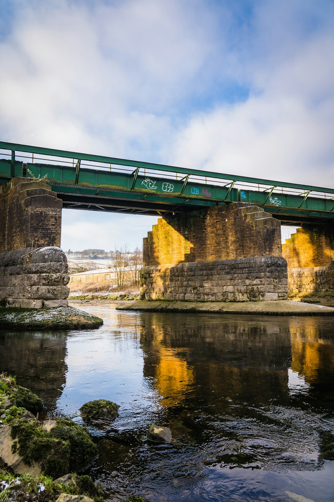 brown concrete bridge over river under cloudy sky during daytime