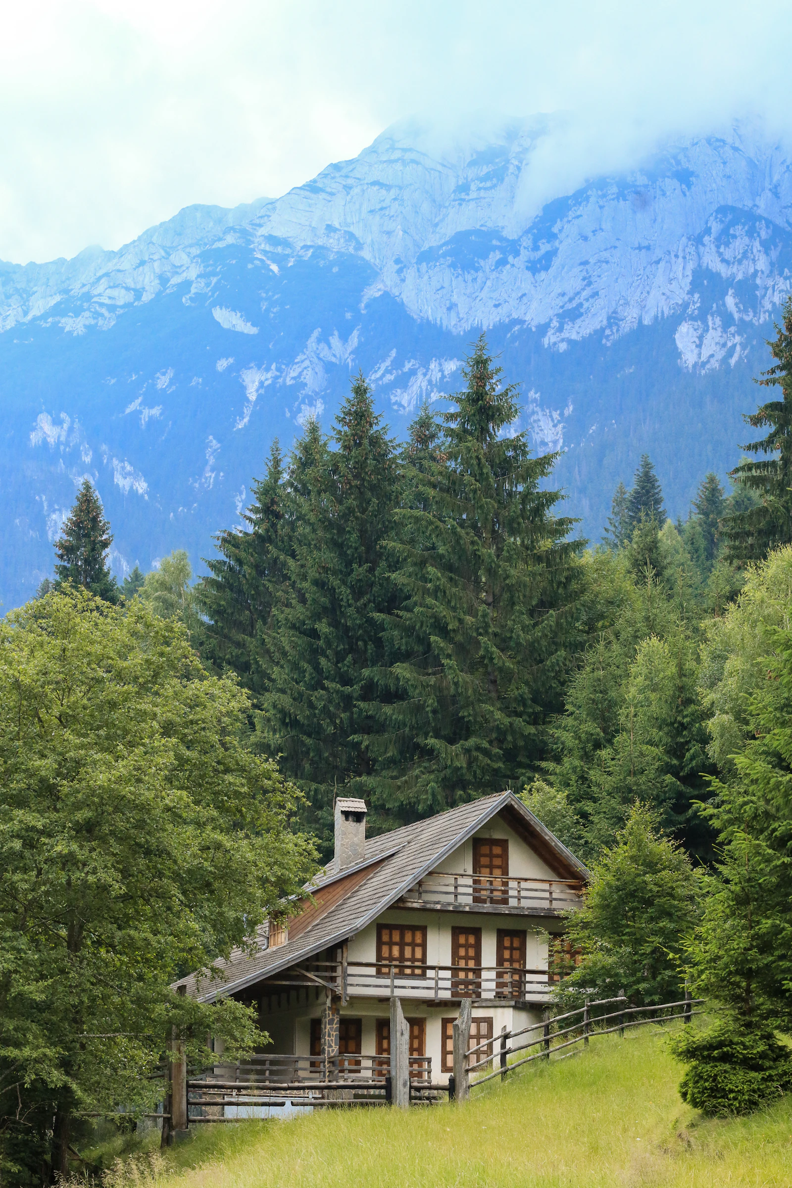 Wooden mountain home surrounded by green trees with a mountain backdrop