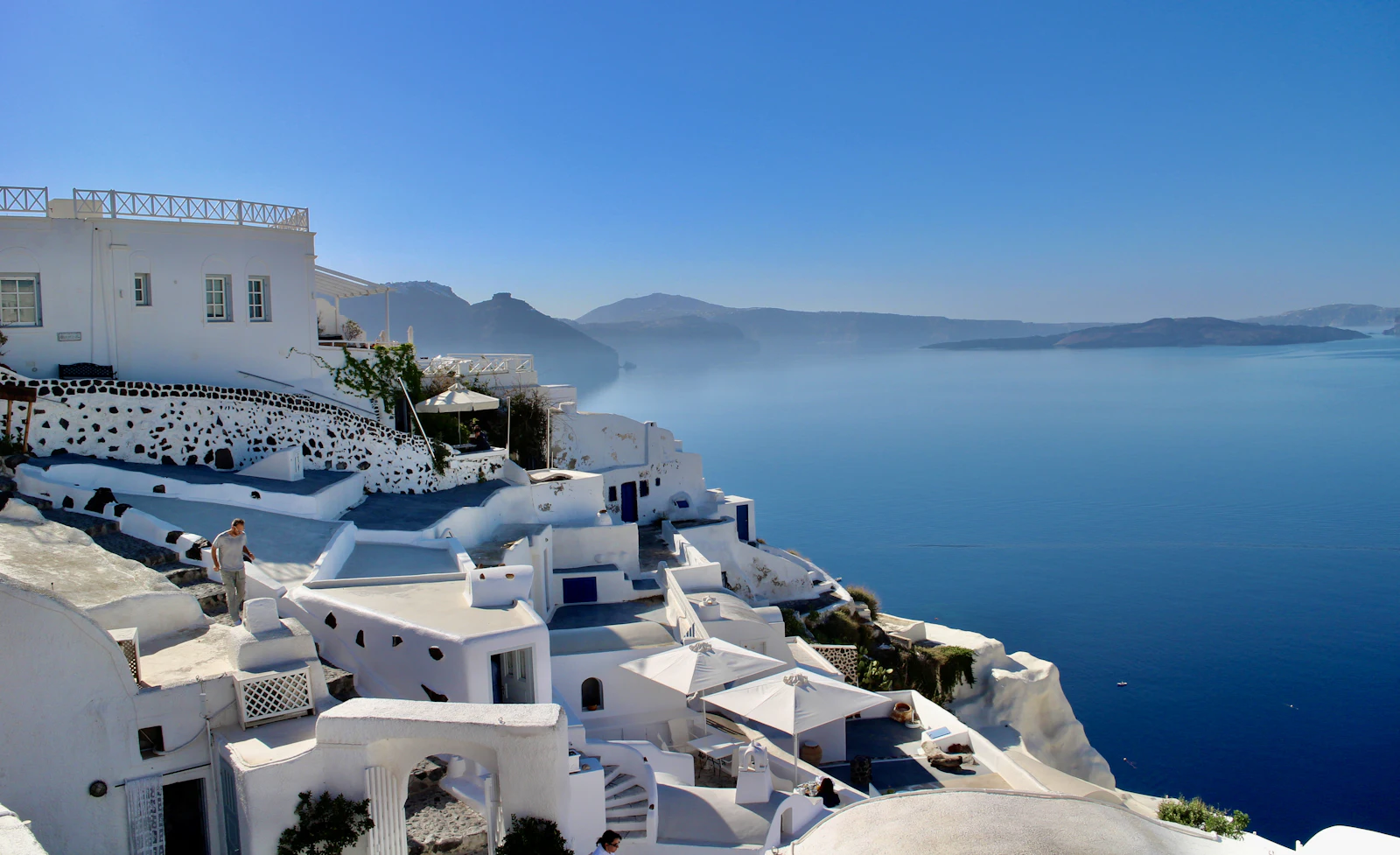 White-washed houses on a Greek island cliff above a deep blue sea