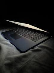 Open laptop on a dark desk with a tech blog open on screen.
