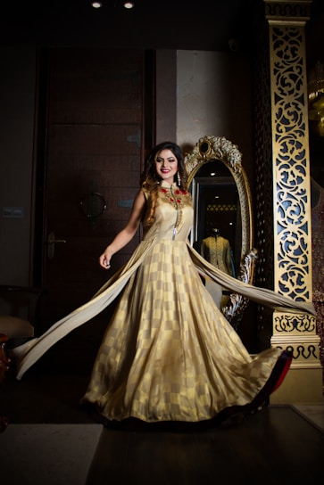 Elegant woman wearing a flowing rose gold dress in a softly lit urban setting