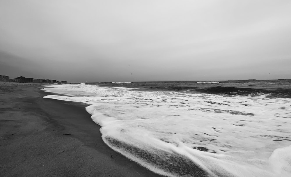 grayscale photo of sea waves crashing on shore