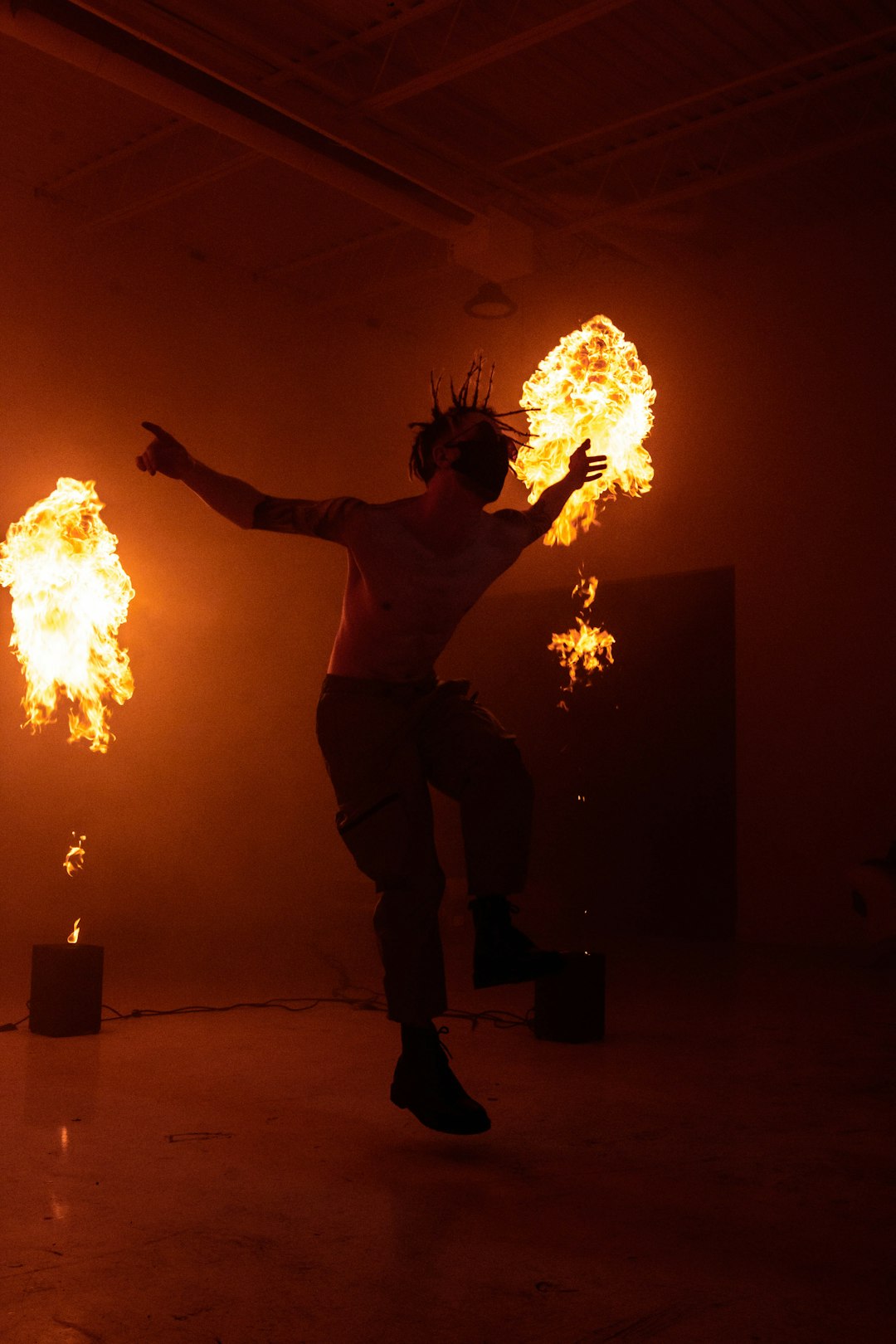 topless man in black pants holding fire