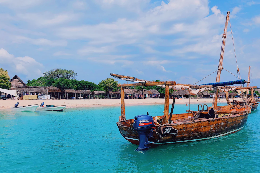 A traditional wooden dhow anchored on the turquoise shallows of a Zanzibar beach, Tanzania