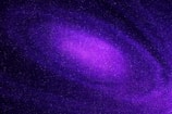 A vibrant, swirling galaxy filled with countless stars, predominantly in shades of purple and violet. Cosmic dust and nebulae create a mesmerizing celestial pattern.