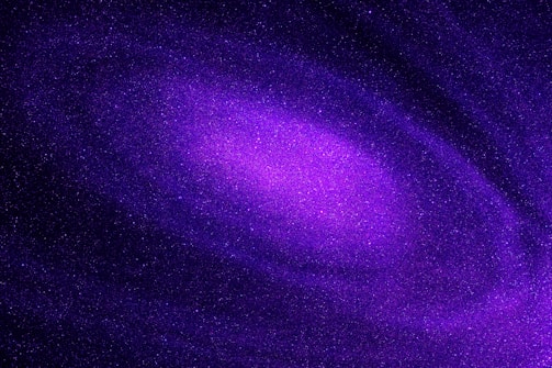 A vibrant, swirling galaxy filled with countless stars, predominantly in shades of purple and violet. Cosmic dust and nebulae create a mesmerizing celestial pattern.