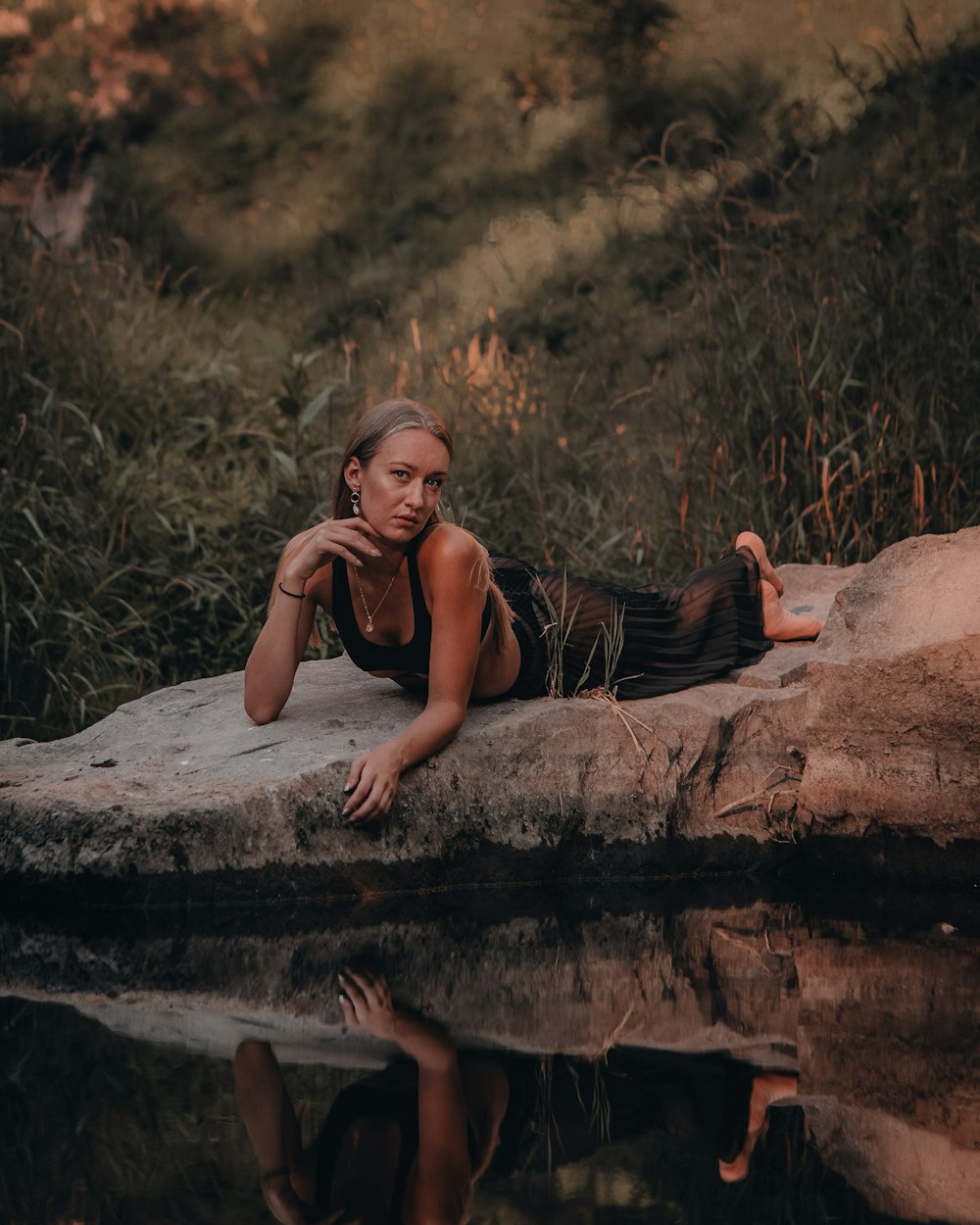 woman in black and white stripe tank top lying on brown rock