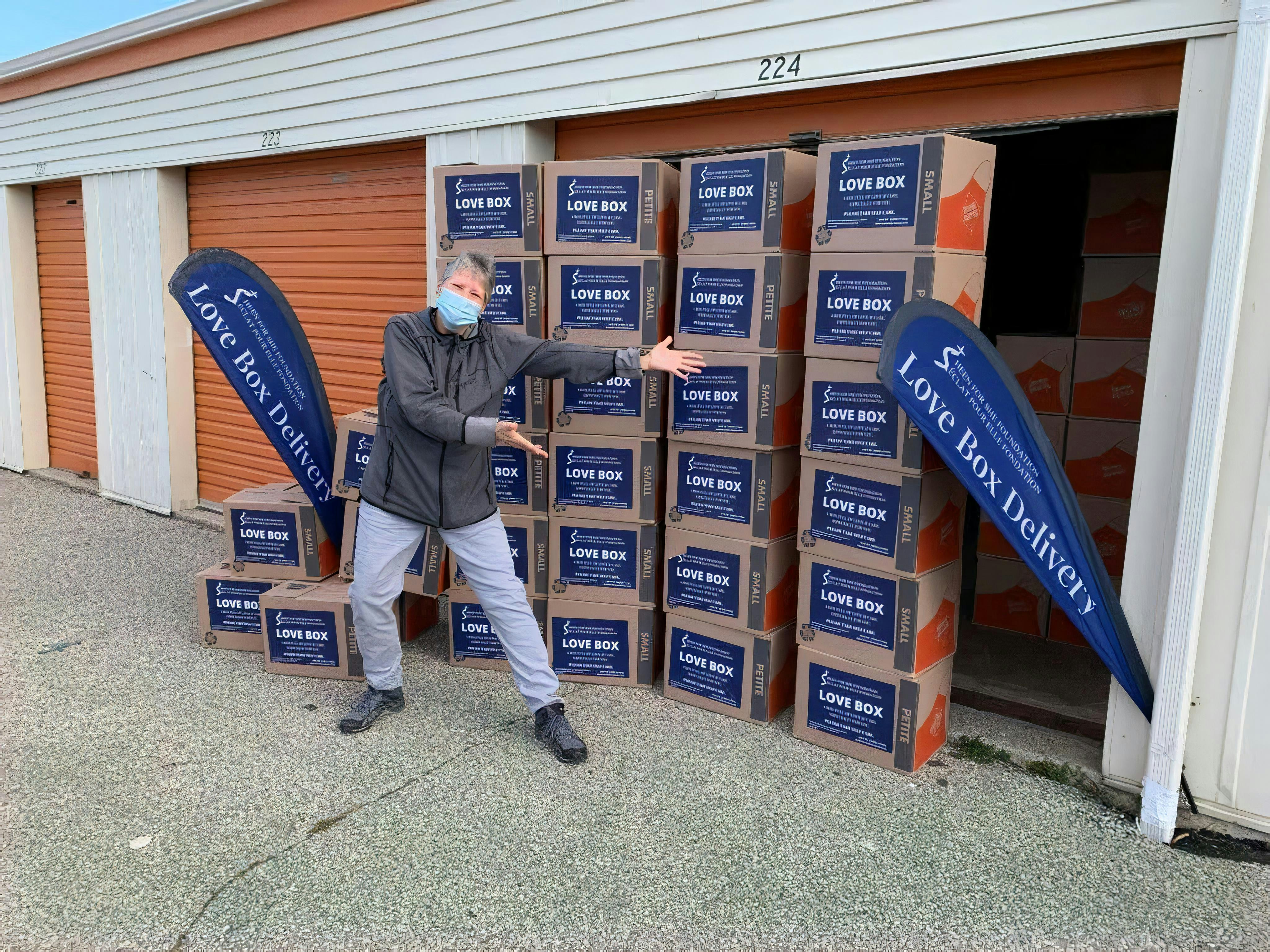 man in gray jacket and gray pants standing beside blue and brown cardboard boxes
