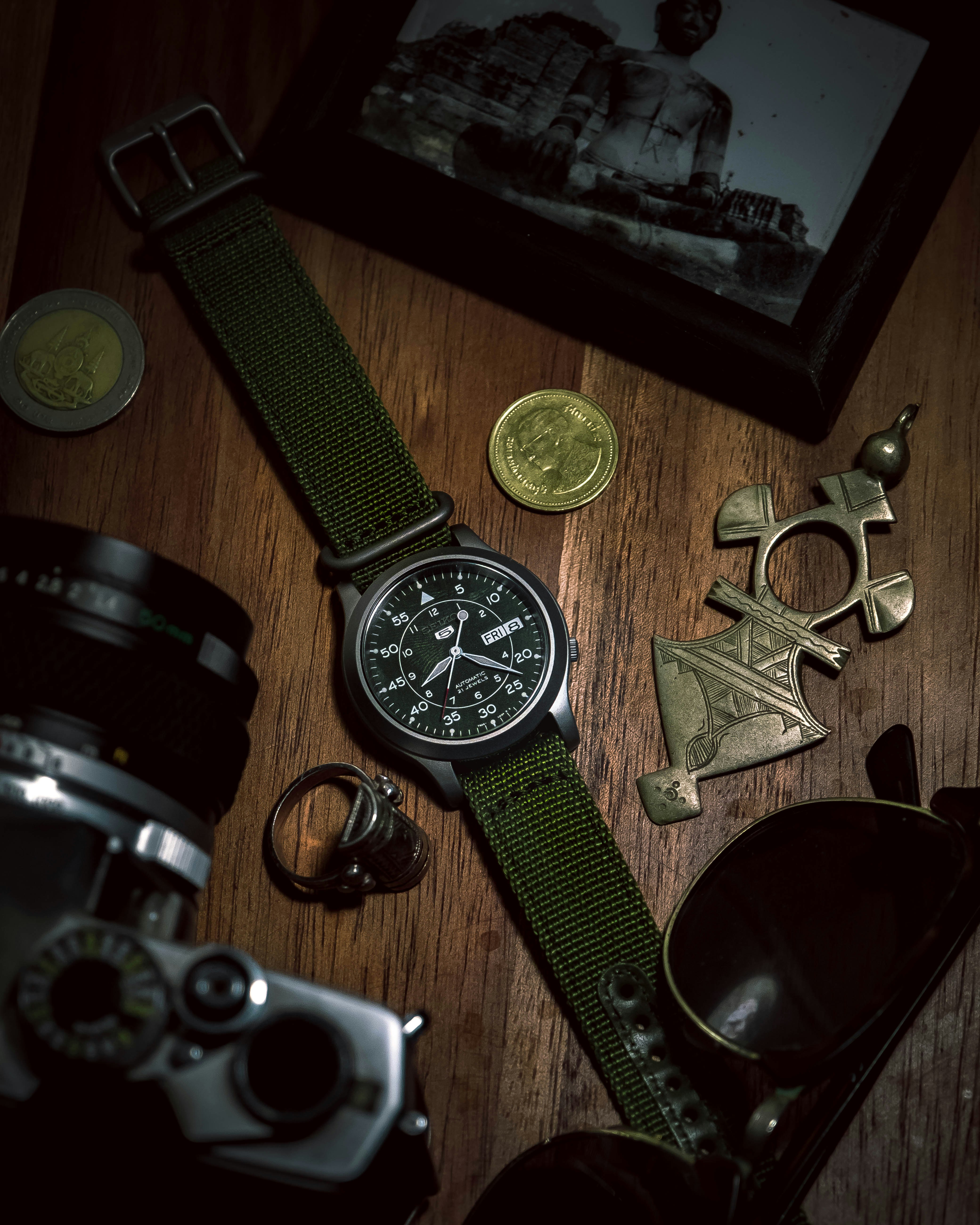 black round analog watch with black leather strap beside silver round analog watch