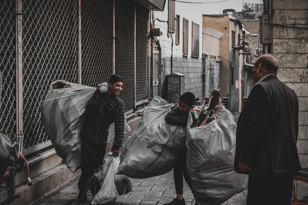 man in black jacket and gray pants holding black plastic bag