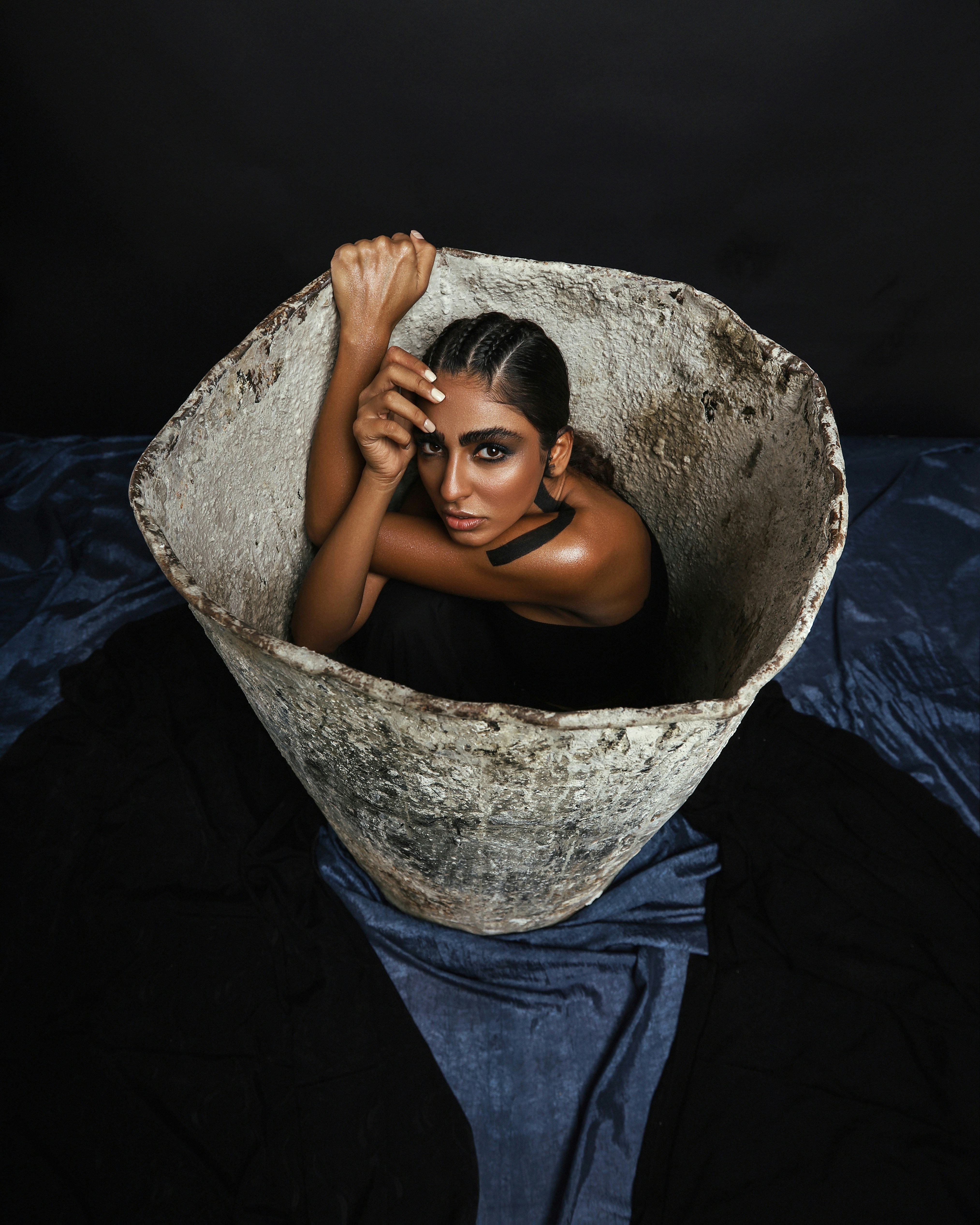 woman in blue denim shorts lying on gray concrete round container
