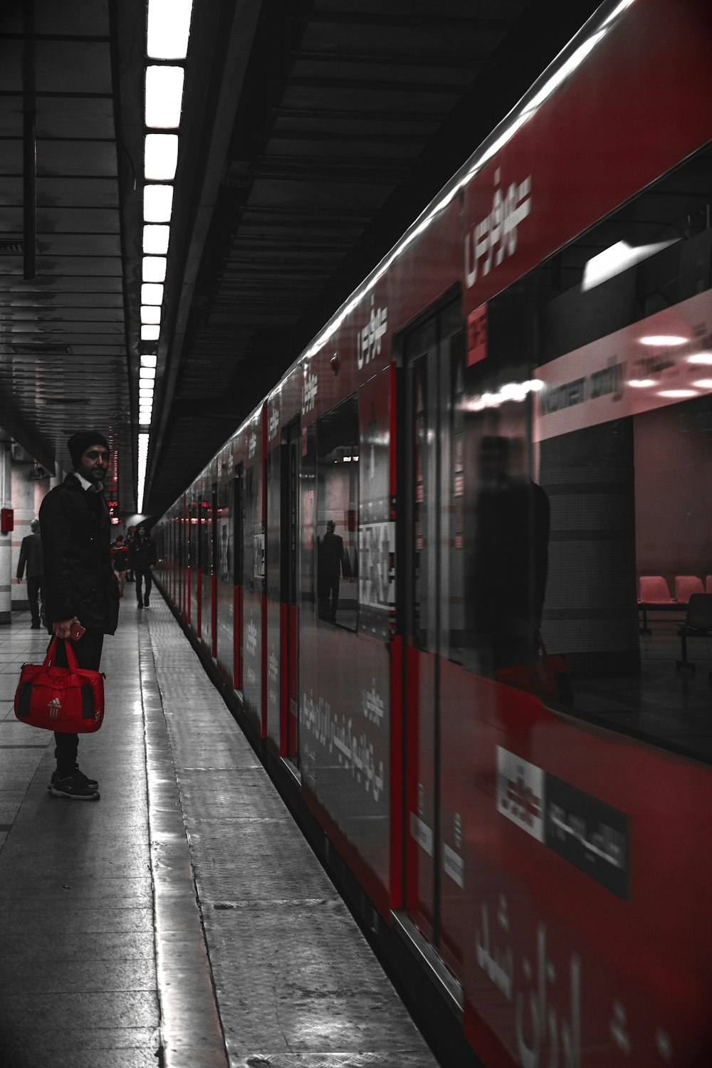 man in black jacket standing beside red train