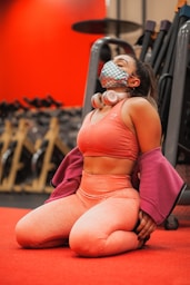 woman in pink tank top and pink pants sitting on red concrete floor
