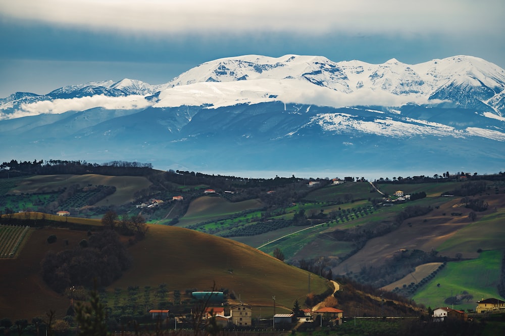 green trees and mountains under white clouds and blue sky during daytime