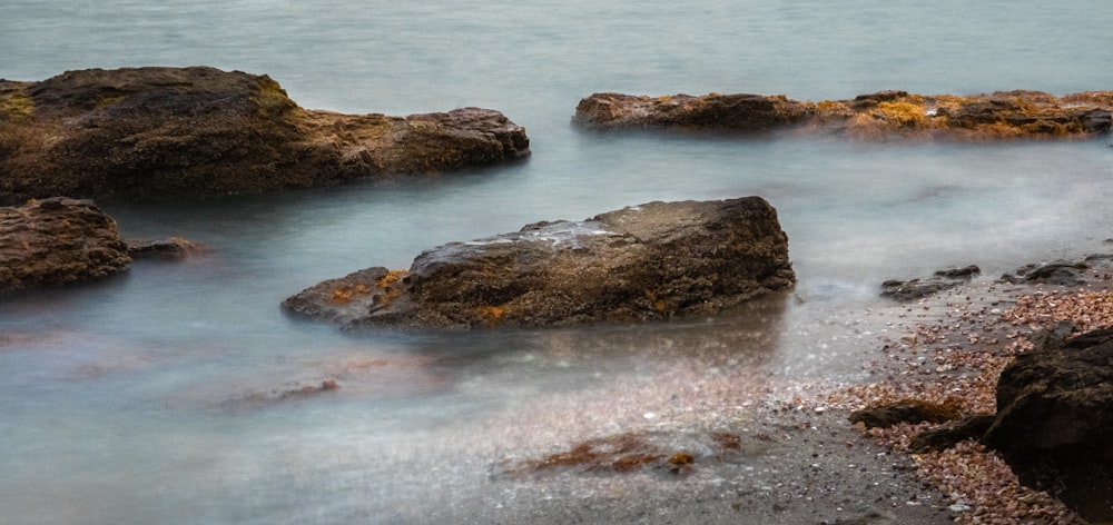 brown rock formation on body of water during daytime