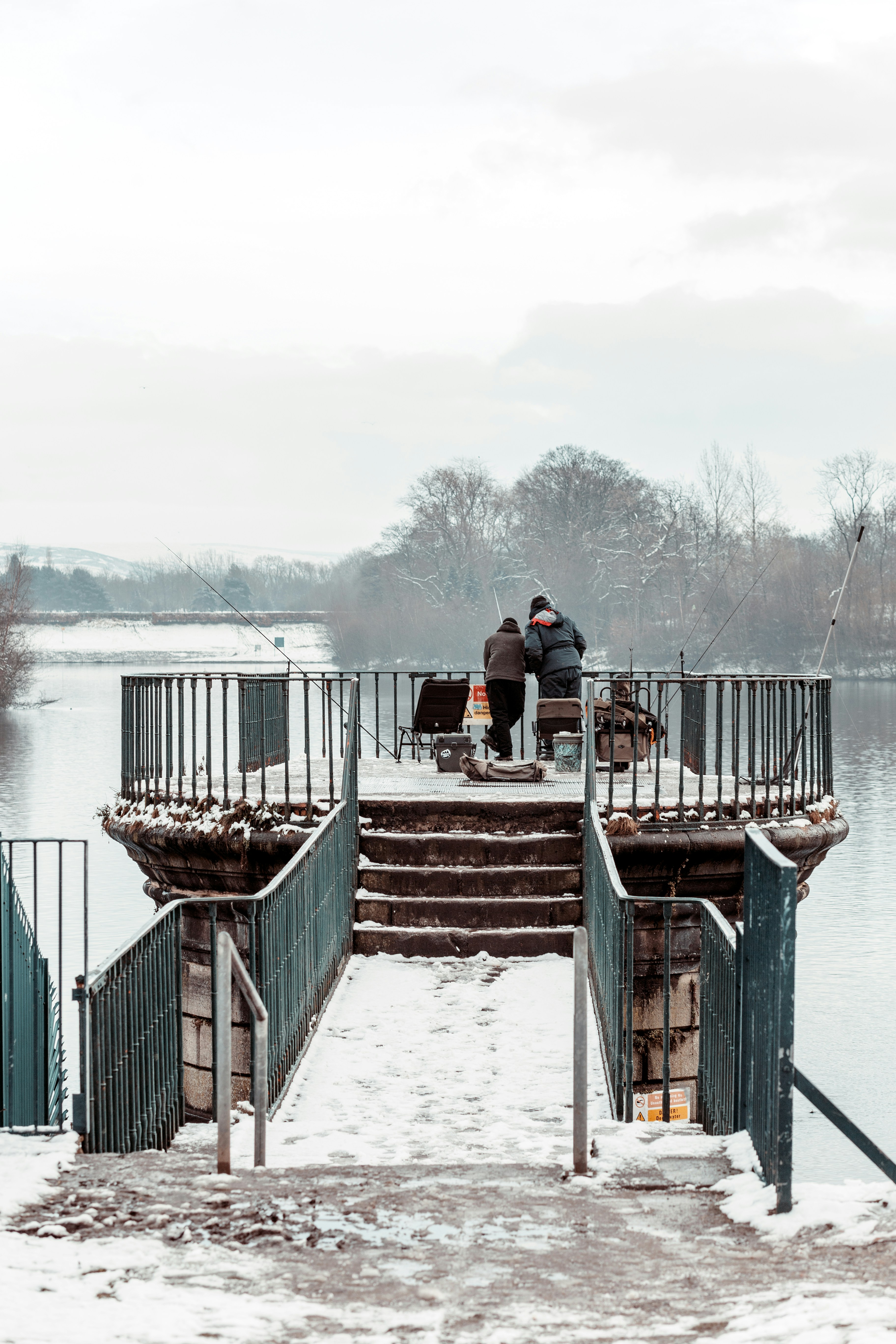 man in red shirt sitting on brown wooden dock during daytime