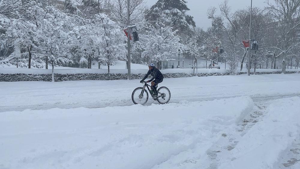 man in black jacket riding on bicycle on snow covered ground during daytime